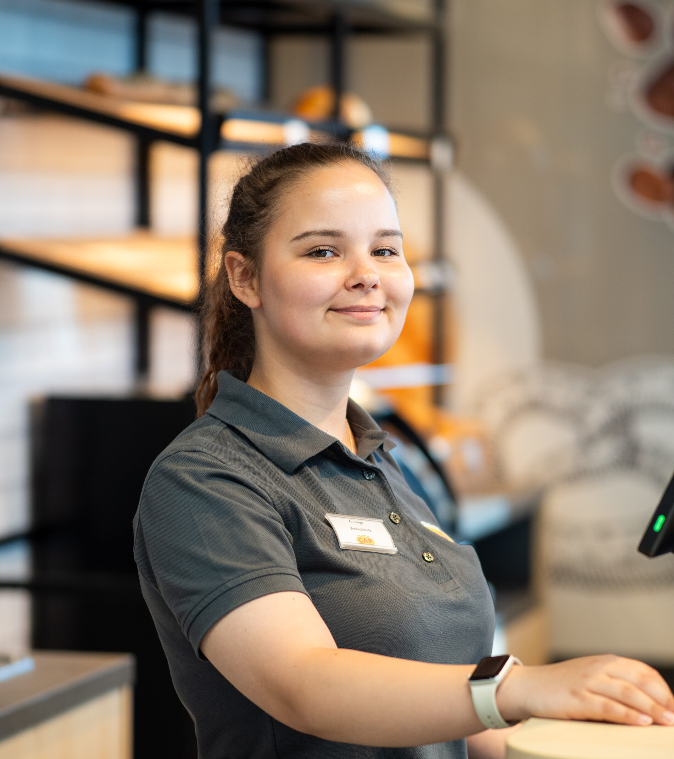 Mitarbeiterin an der Kasse eines inklusiven CAP-Markts von includeo.