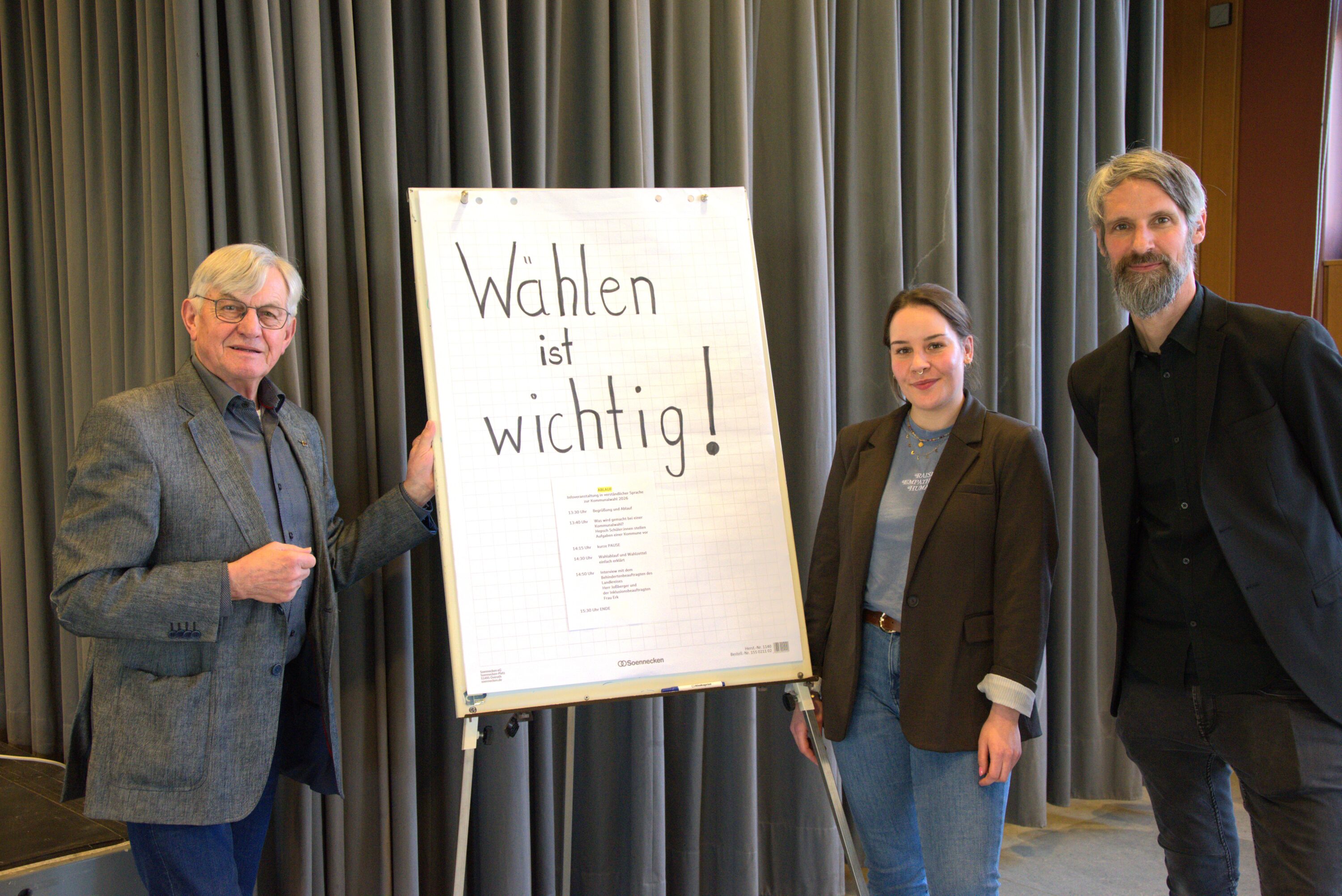 Ernst Joßberger, Frau Erk und Andreas Ullherr stehen neben einem Flipchart mit der Aufschrift „Wählen ist wichtig!“ und informieren über politische Teilhabe sowie die Kommunalwahl in Leichter Sprache.