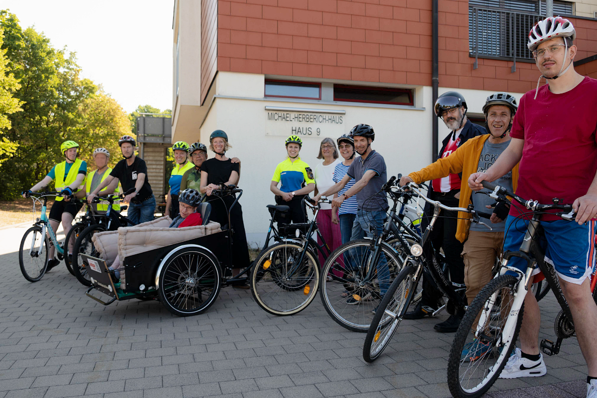 Bewohner des St. Josefs-Stifts und die Begleiterinnen des Fahrrad-Sicherheitstrainings stehen mit Fahrrädern und Helmen gemeinsam auf dem Stiftsgelände