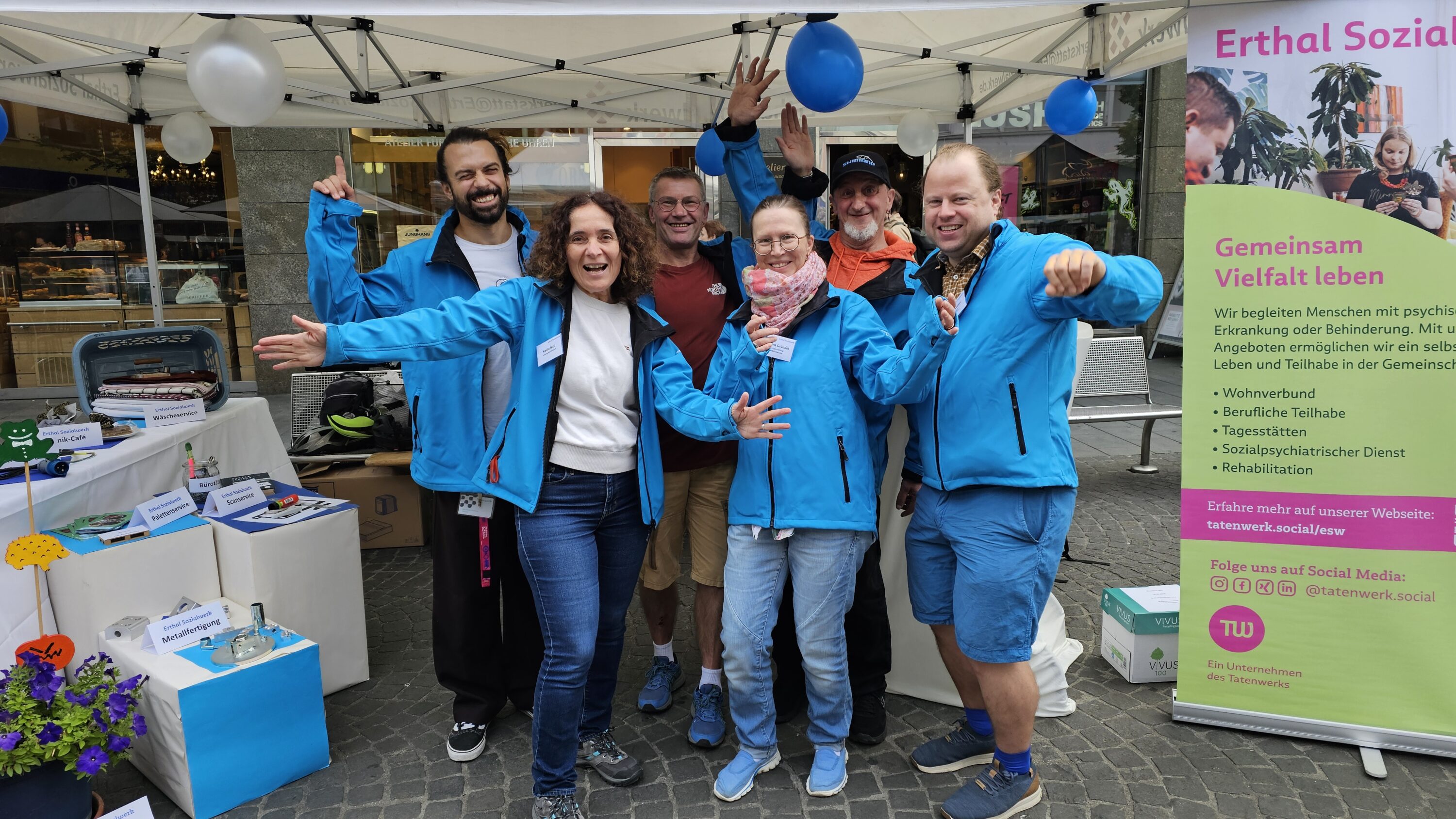 Mitarbeitende und Personal der WfbM des Erthal-Sozialwerks stehen gut gelaunt am Informationsstand auf dem Würzburger Stadtfest.