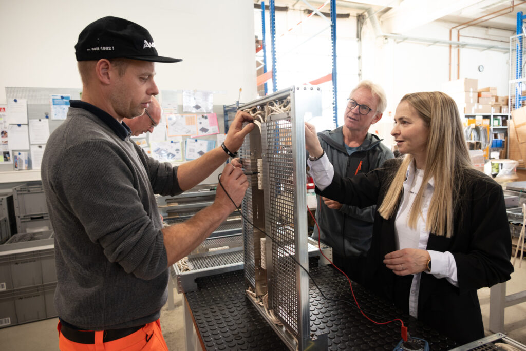 Zwei Teilnehmer arbeiten unter der Anleitung des Abteilungsleiters an der Verkabelung einer aufgestellten Elektrobaugruppe.
