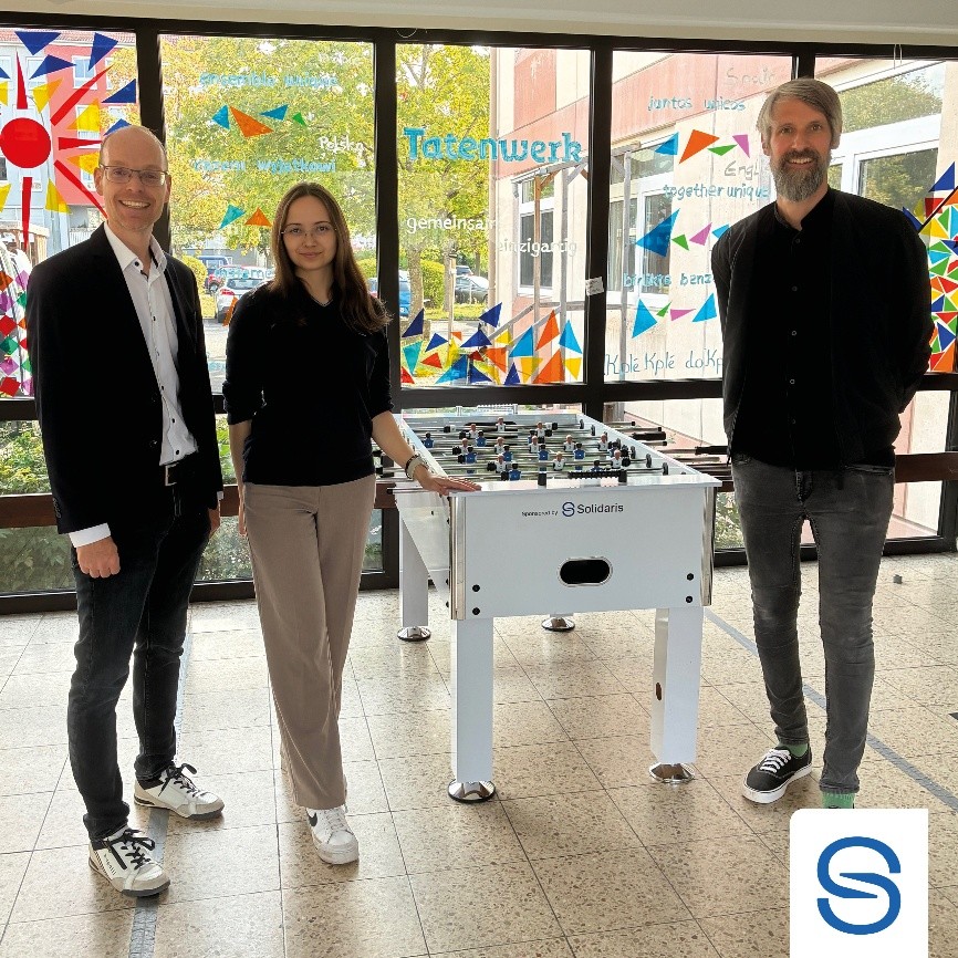 Jochen Wältz, Elisabeth Gaspert und Andreas Ullherr stehen von links nach rechts neben dem gespendeten Tischkicker der Robert-Kümmert-Akademie.
