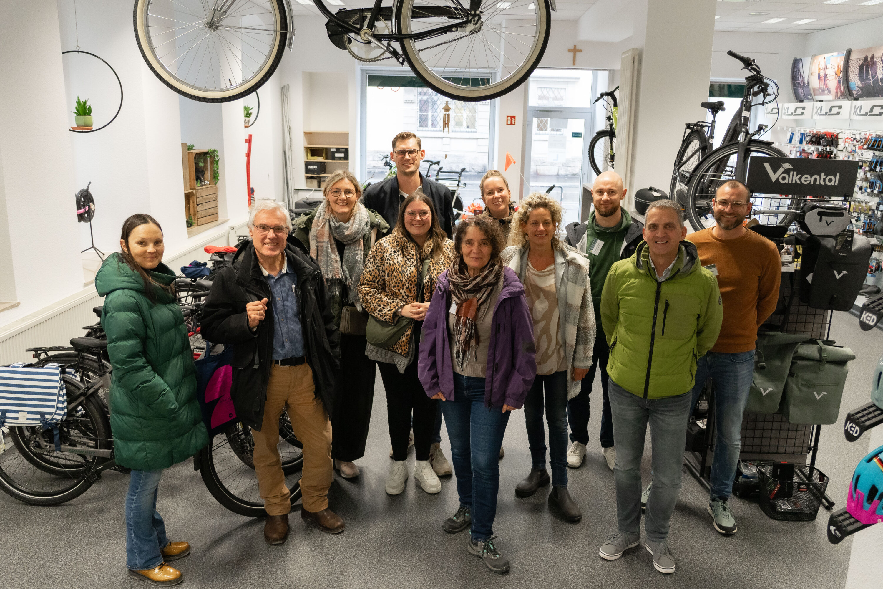 Gruppenbild der Gäste der Deutschen Rentenversicherung mit Vertreter:innen des Erthal-Sozialwerks zwischen Fahrrädern im Verkaufsraum.