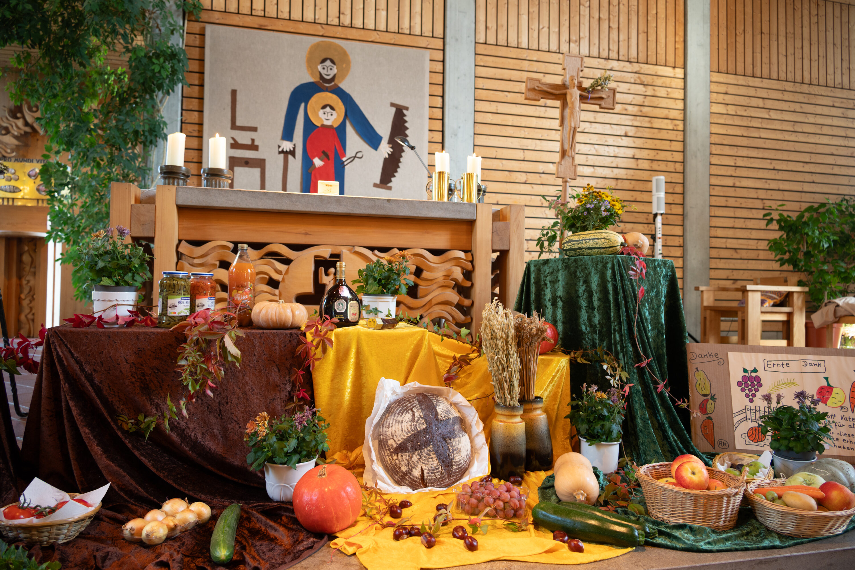 Erntedankaltar im St. Josefs-Stift mit Brot, Kürbissen, Obst, Gemüse und Getreideähren, geschmückt mit Blumen und bunten Tüchern.
